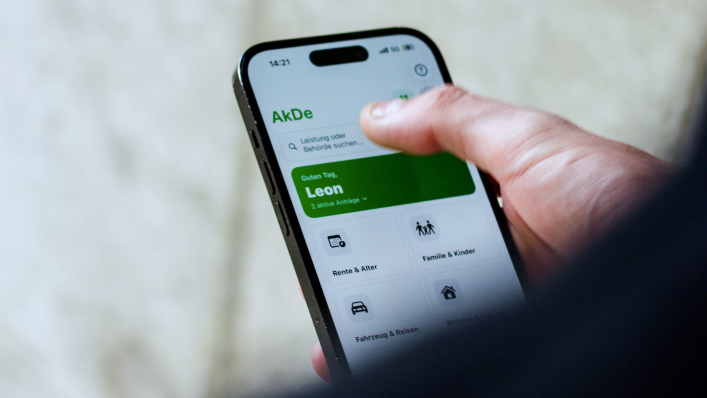 Hand hält ein iPhone mit der Startseite von AkDe